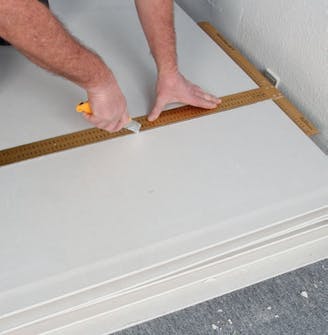 Gipsskivor tak: Skär igenom kartongen på framsidan med en hobbykniv Gipsskivor tak: Skär igenom kartongen på framsidan med en hobbykniv